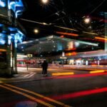 man in black jacket walking on sidewalk during night time